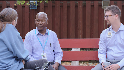 A man sitting on a bench in an outdoor setting.