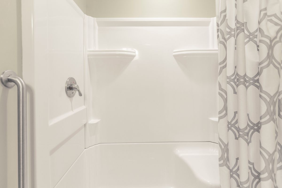 A modern, clean white shower space with built-in shelves.