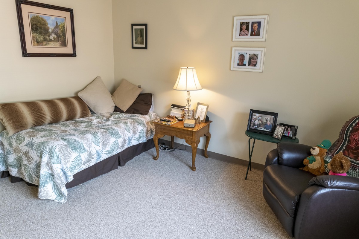 A cozy living room with a couch, side table, and framed photographs on the wall.