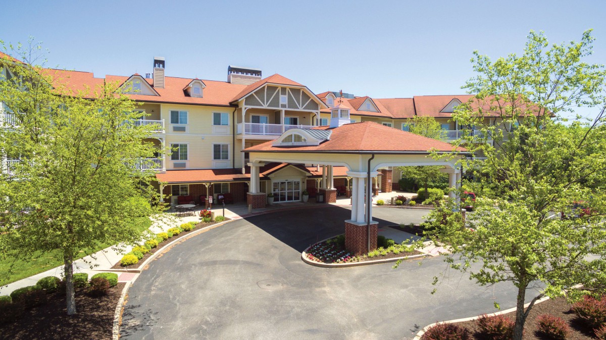 A front view of a hotel with a circular driveway and well-maintained landscaping.