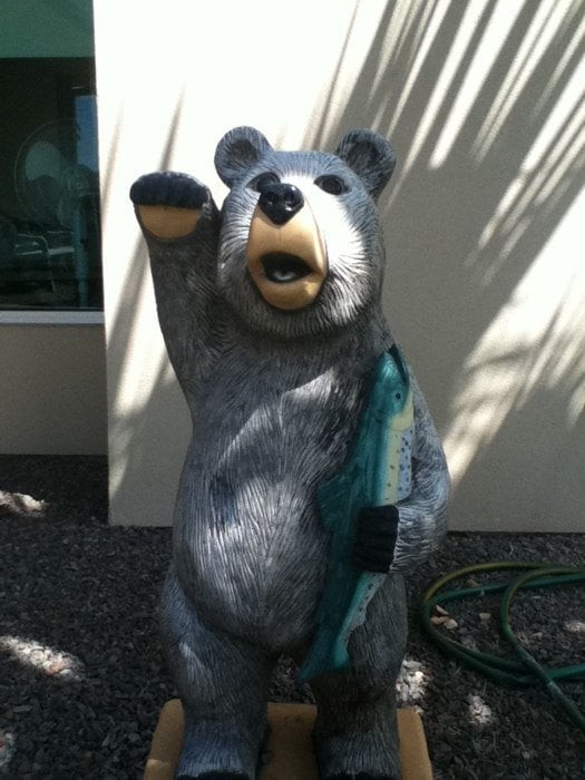 A bear statue holding a fish, located outdoors.