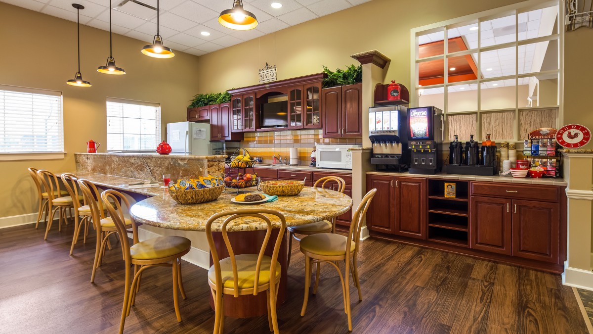 A cozy kitchen with wooden cabinets and a round dining table, complemented by warm lighting.