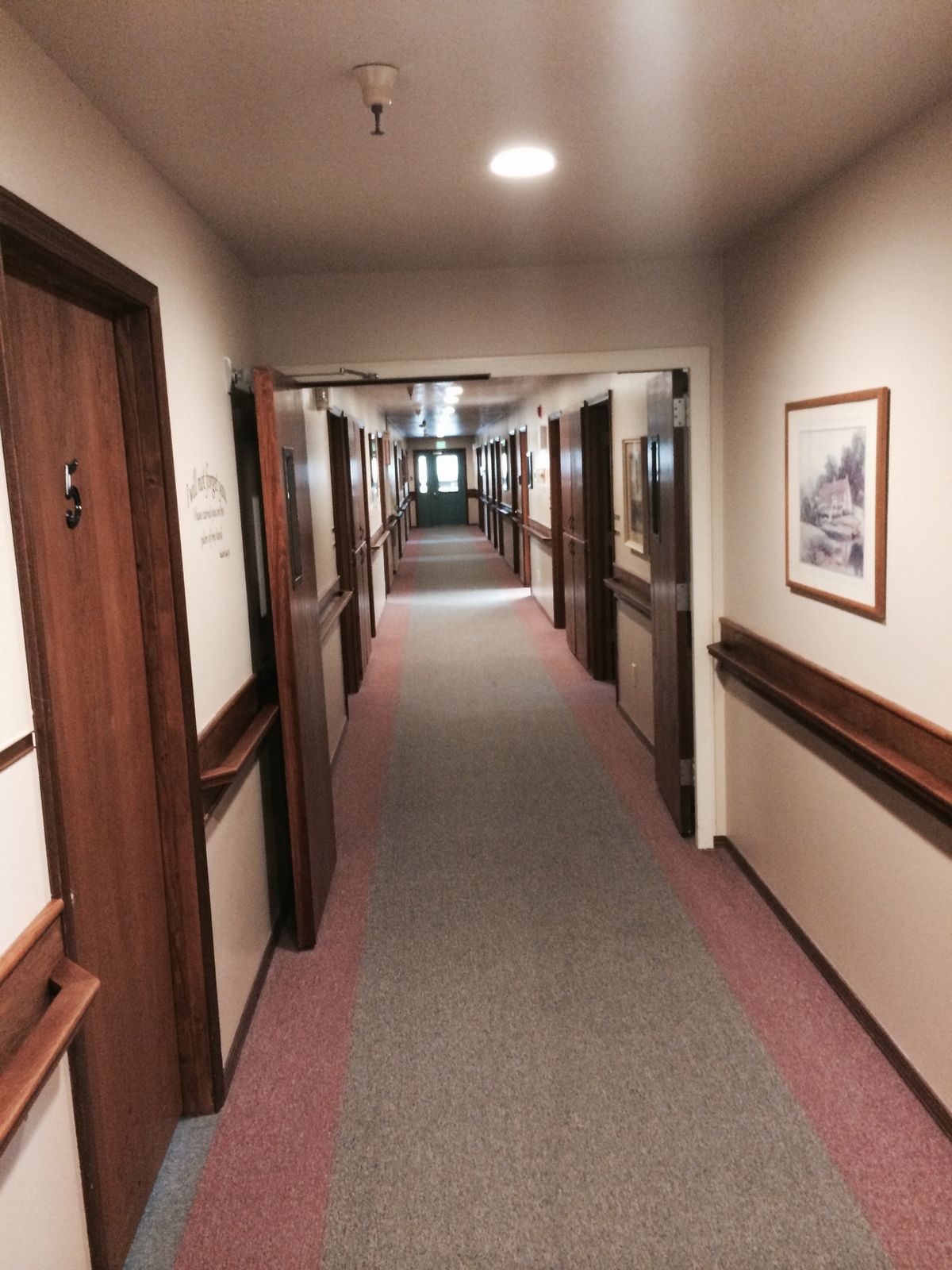 A well-lit hallway with multiple doors on either side, resembling a hotel corridor.