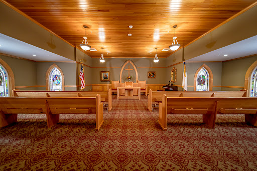A peaceful interior view of a church, featuring wooden pews and soft lighting.