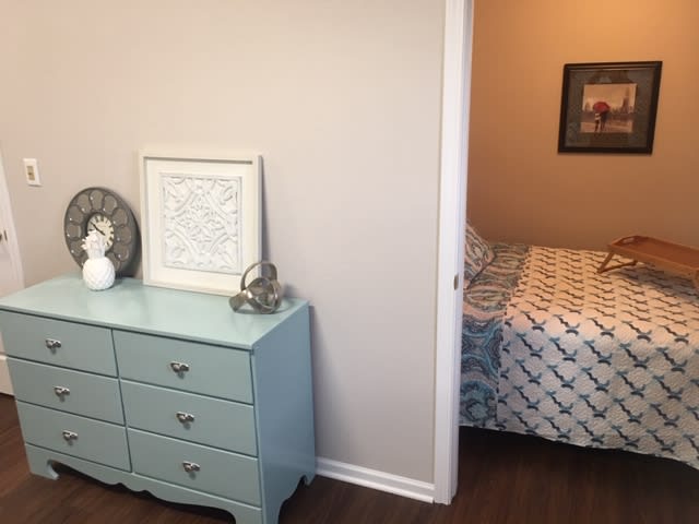A cozy bedroom interior with a light blue dresser and patterned bedding.