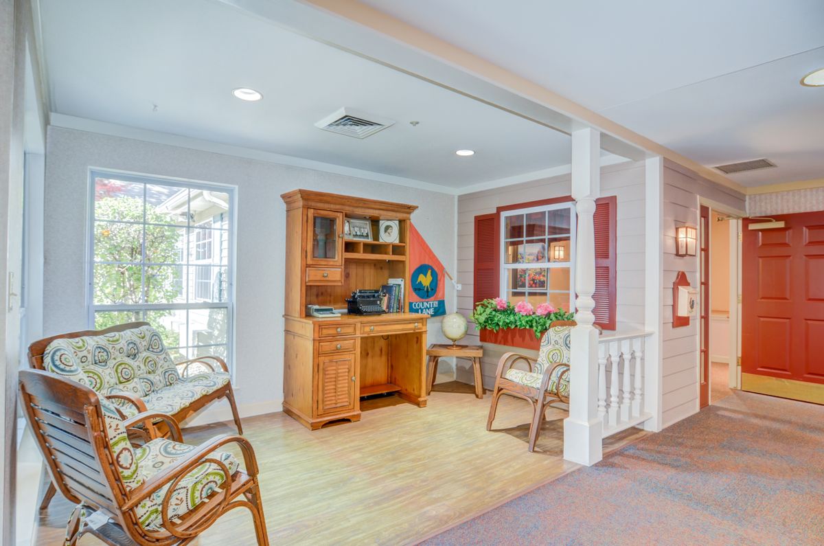 A cozy home office space with a wooden desk, chairs, and decorative elements by the window.