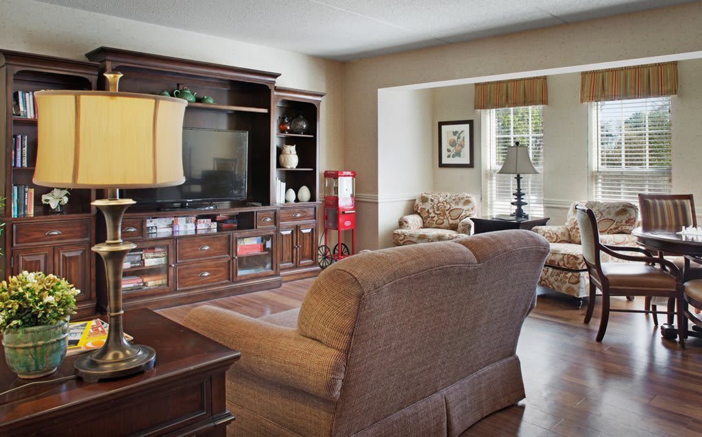 A cozy living room with a sofa, entertainment center, and a large window providing natural light.