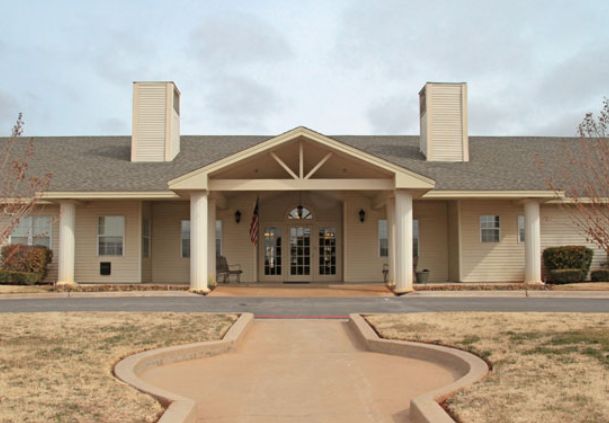A symmetrical building with a prominent entrance featuring columns and a gabled roof.
