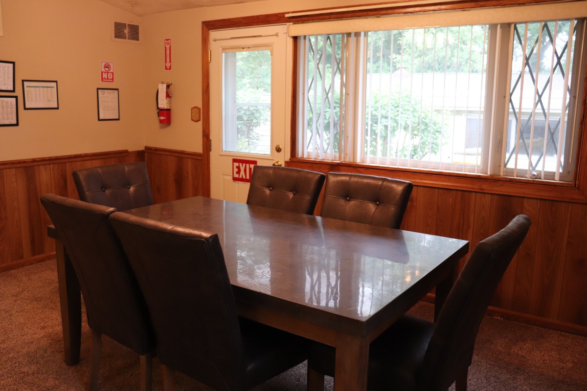 A dining room with a table and chairs by a window.