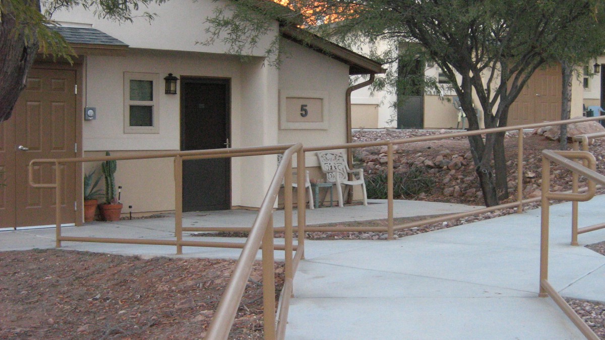 A house with a ramp and chairs on the porch.