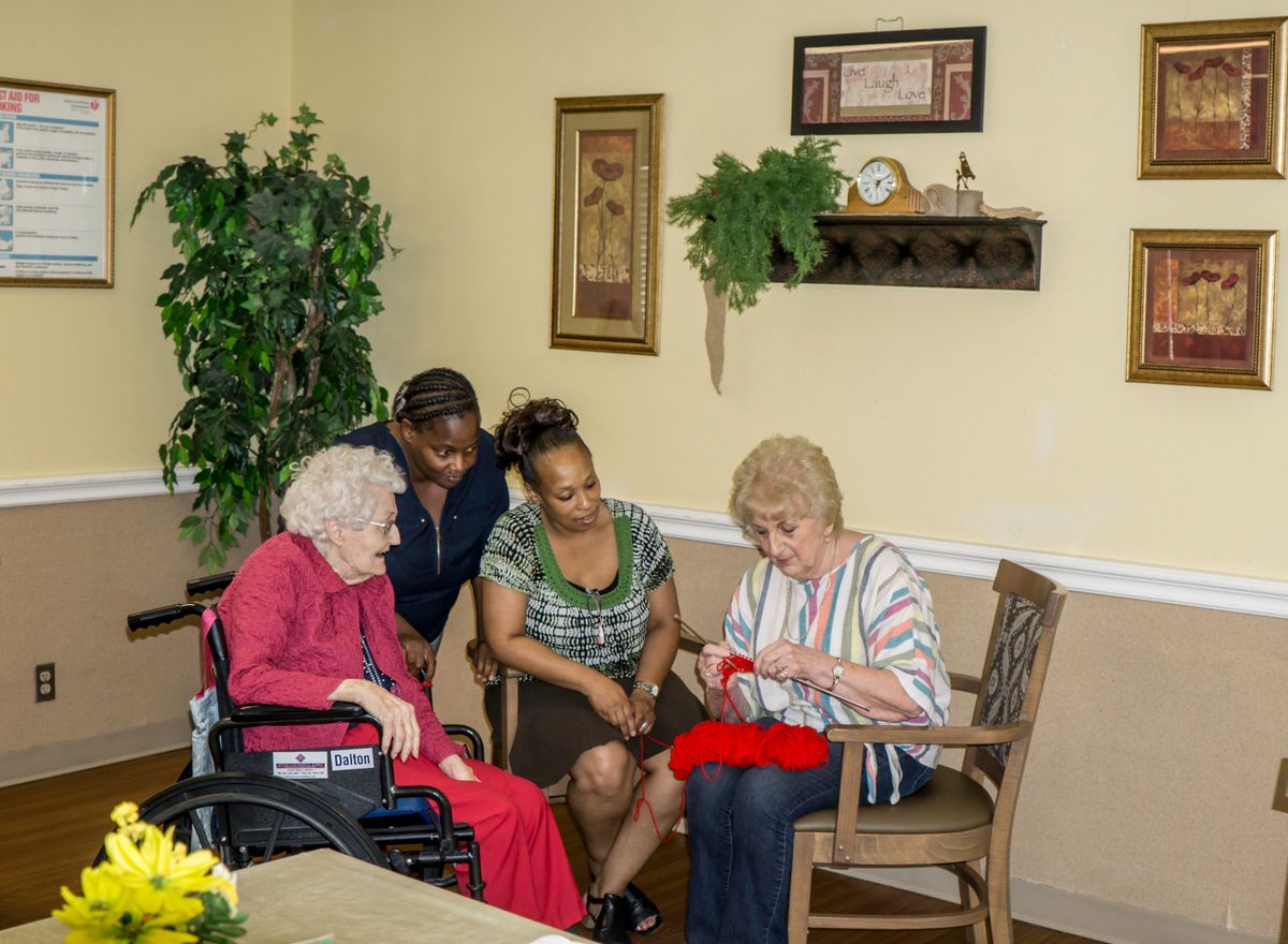 A group of people gathered in a care facility, engaging in a social activity.