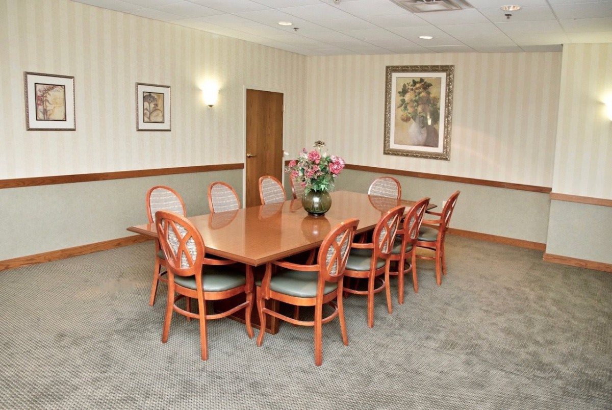 A well-organized conference room with a wooden meeting table and chairs, decorated with art pieces on the walls.