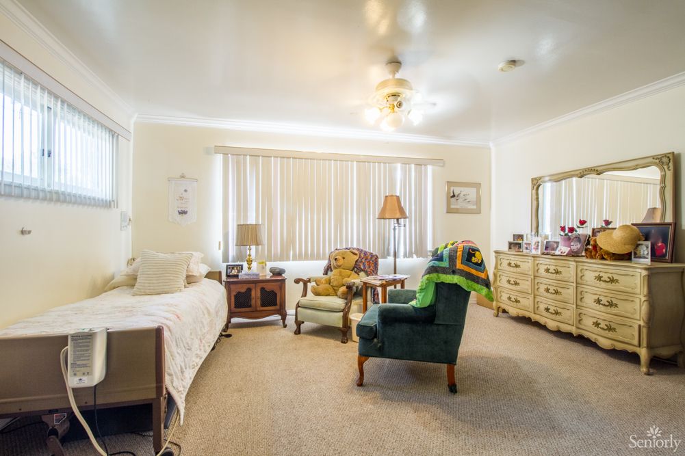 A cozy bedroom with a bed, chairs, and dressers.