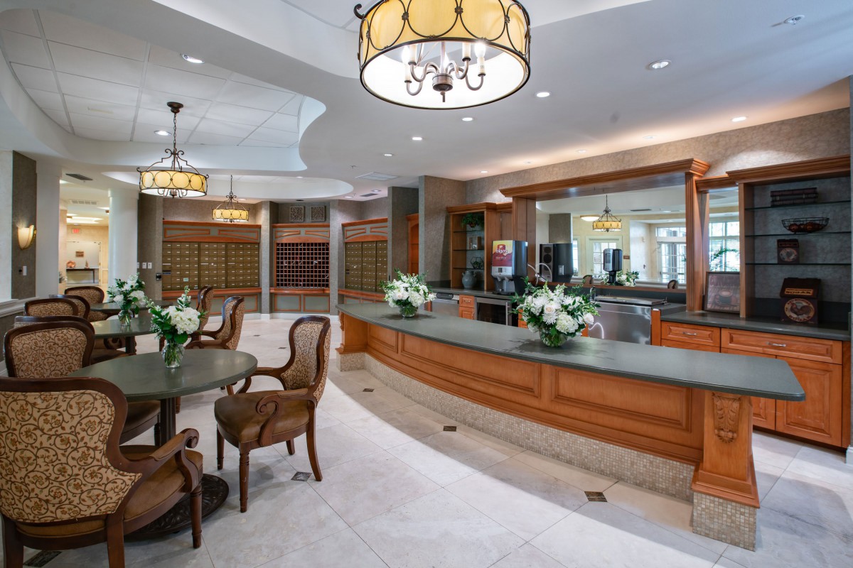 A well-furnished lobby with a reception desk and seating area, decorated with chandeliers and floral arrangements.