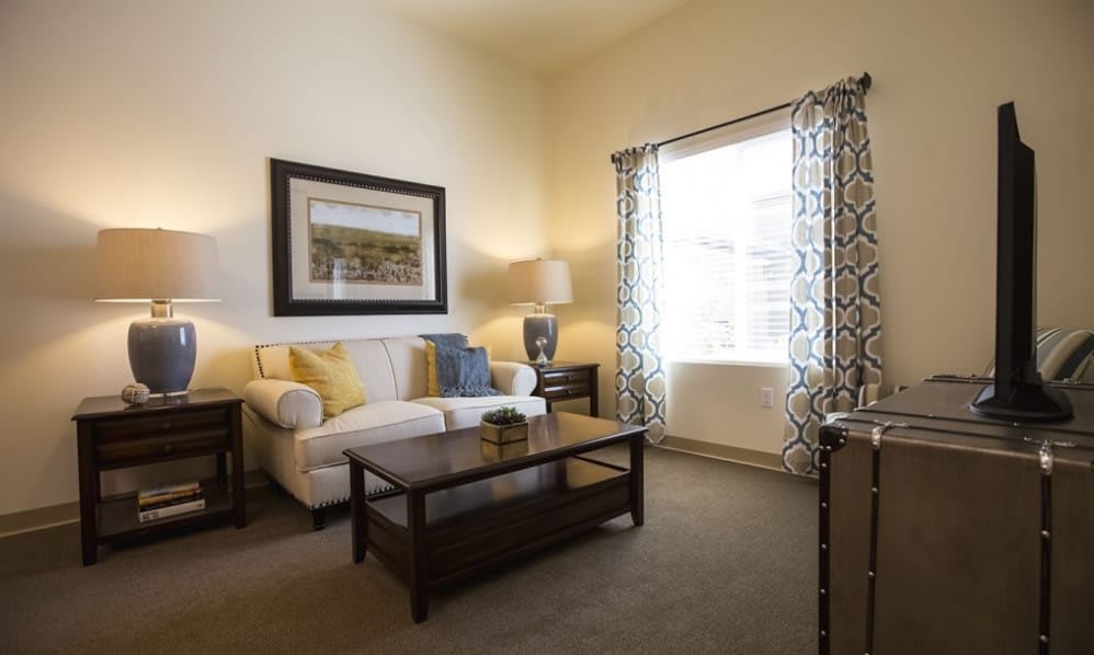 A cozy living room with a sofa, coffee table, and a large window letting in natural light.
