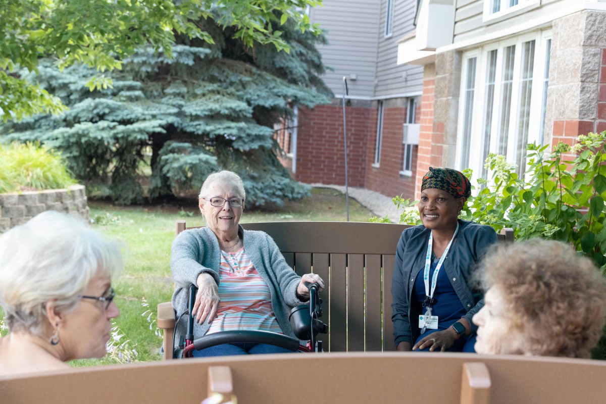 A group of people enjoying a conversation outdoors in a garden setting.