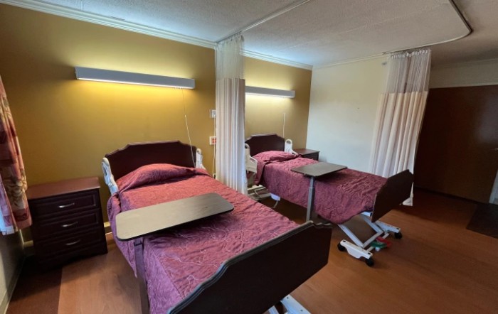 A hospital room with two patient beds and privacy curtains.