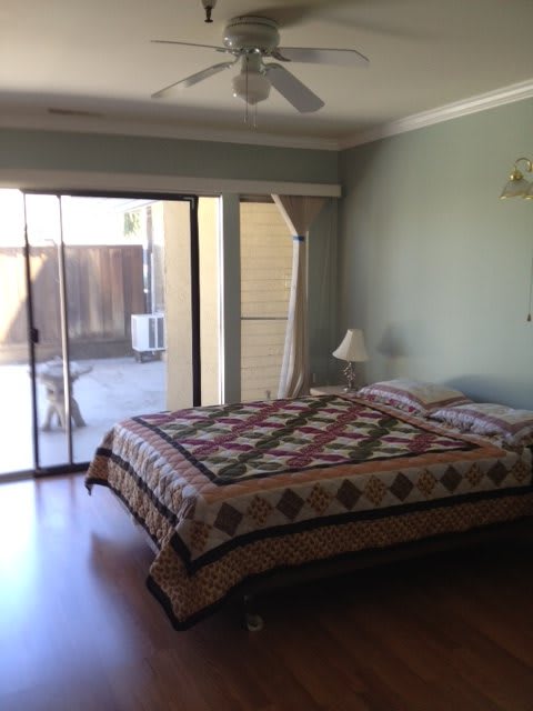 A cozy bedroom with a quilt-covered bed and sliding glass door.