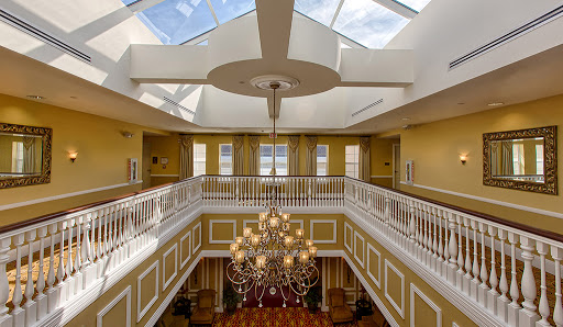 An elegant lobby featuring a stunning chandelier and skylight, complemented by yellow walls and a beautiful balcony.