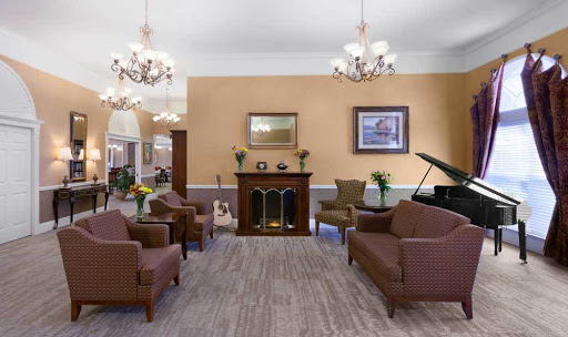 A cozy lounge area featuring comfortable seating, elegant chandeliers, and a classic fireplace.