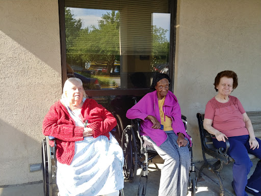 Three elderly women enjoying a sunny day outdoors in their wheelchairs.