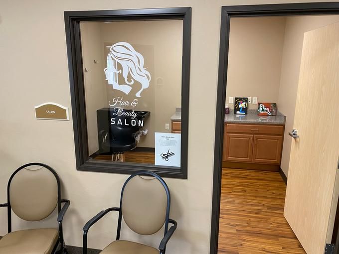 A small salon interior with a waiting area, featuring chairs and decorative window signage.