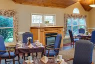 A cozy dining room with a fireplace and neatly arranged tables and chairs.