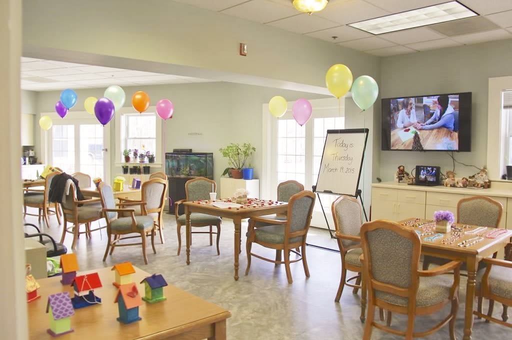 A decorated community center room with tables, chairs, and colorful balloons.