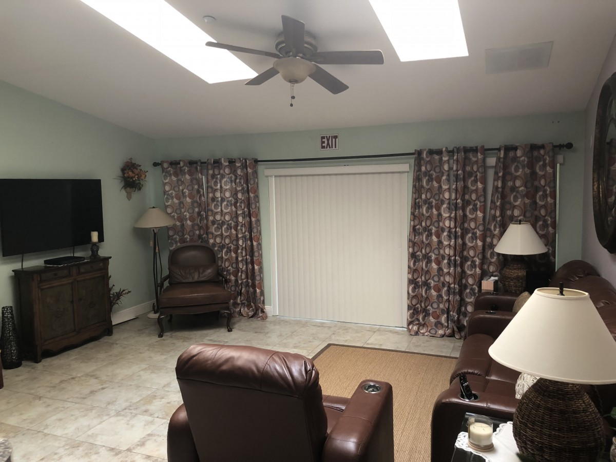 A cozy living room with leather armchairs, a ceiling fan, and patterned curtains.