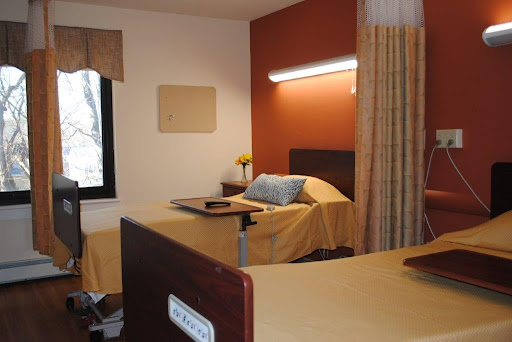 A well-furnished hospital room with a bed, window, and soft lighting.