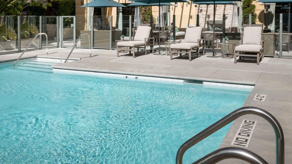 Outdoor swimming pool with lounge chairs and umbrellas.