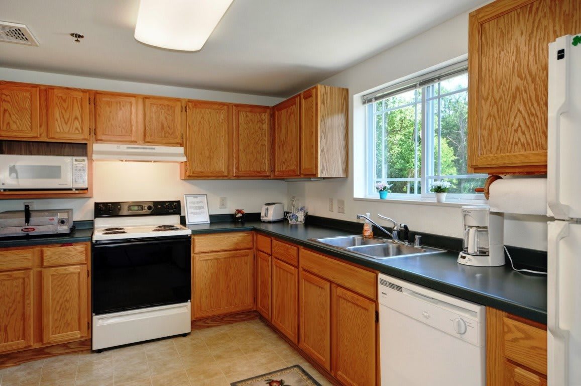 A modern kitchen with wooden cabinets, a stove, and a window above the sink.