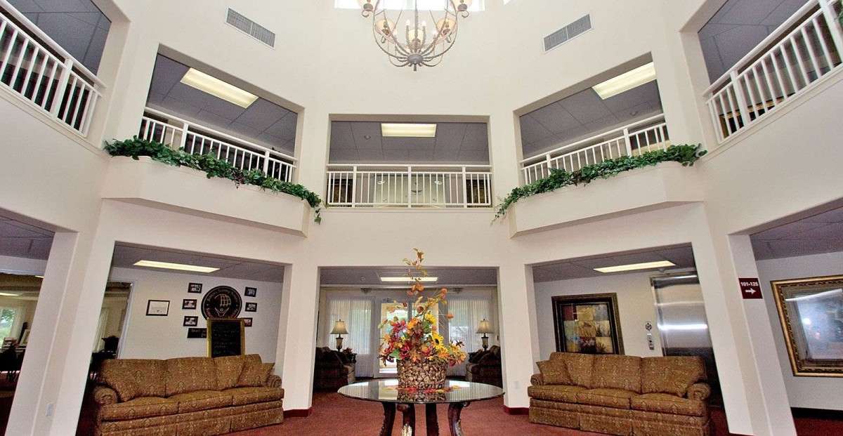 A spacious lobby with a chandelier, sofas, and decorative flowers.