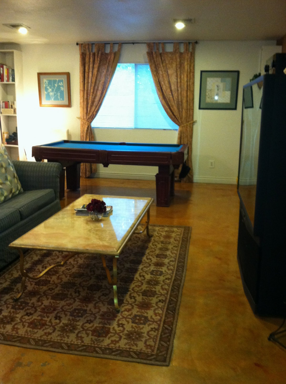 A cozy living room featuring a billiard table, a comfortable sofa, and a decorative rug.