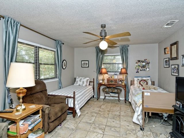 A cozy bedroom with two single beds, a desk between them, and a ceiling fan.