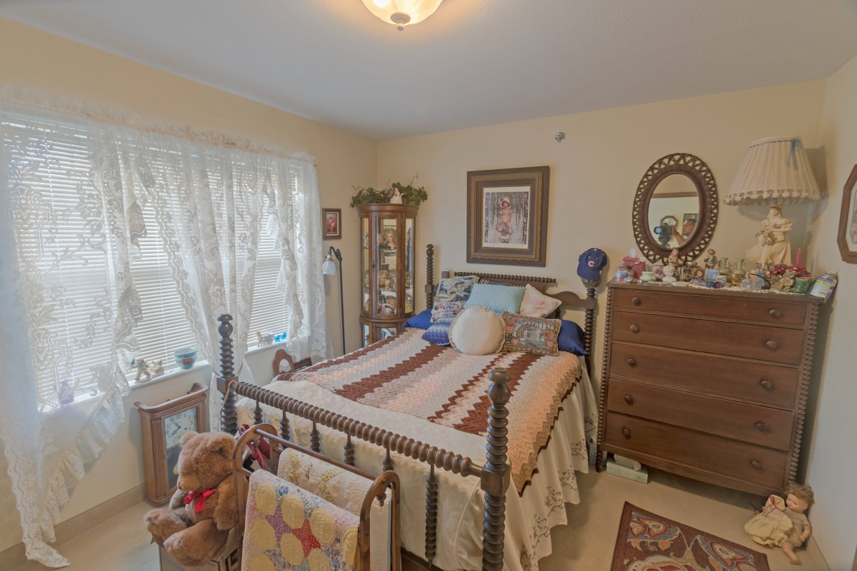 A cozy bedroom featuring a quilt-covered bed and wooden furniture.