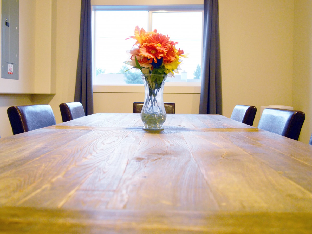 A dining table with a vase of colorful flowers near a window.