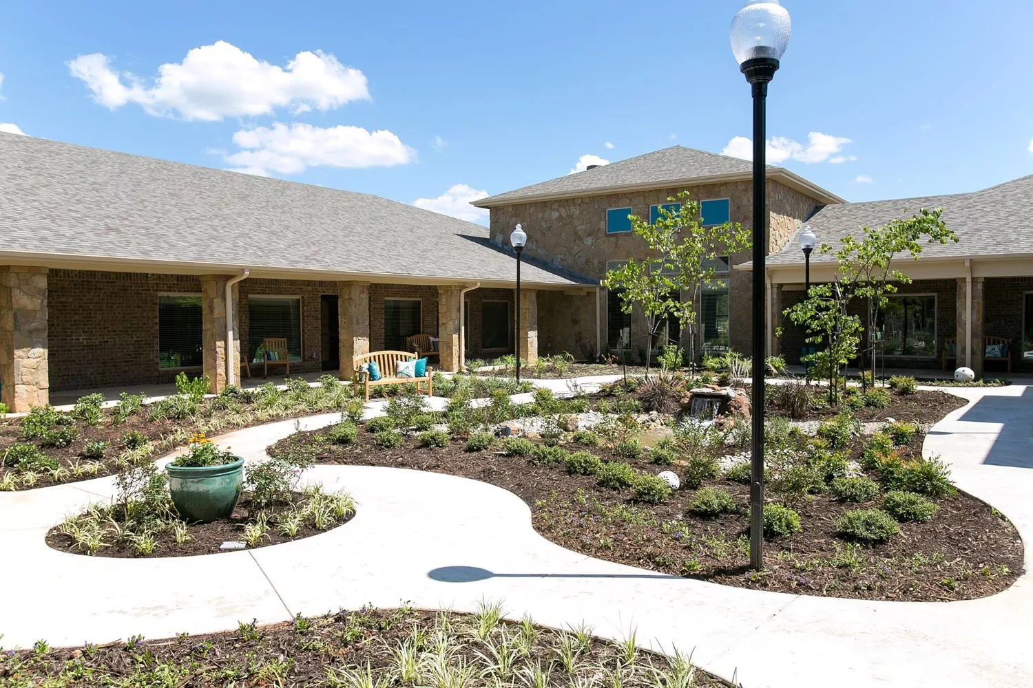 A modern building surrounded by landscaped gardens and pathways under a clear blue sky.