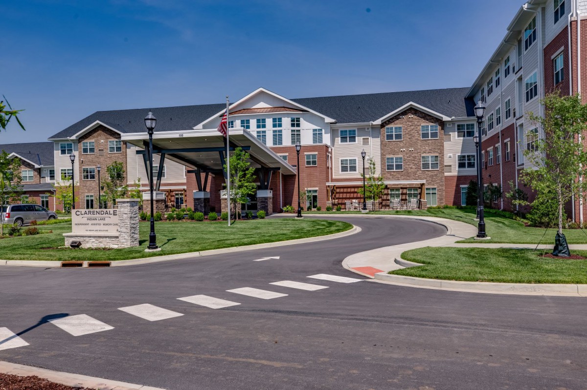 A modern residential building with well-maintained landscaping and a curving driveway.