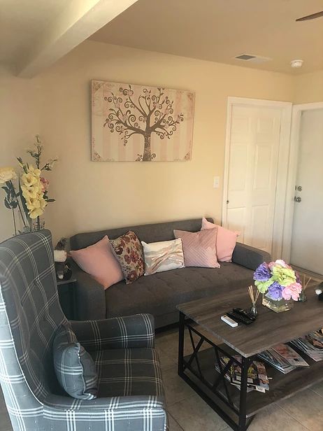 A cozy living room with a gray sofa, colorful cushions, and a tree wall art piece.