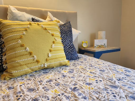 A cozy and vibrant bedroom setup featuring decorative pillows and a floral bedding pattern.