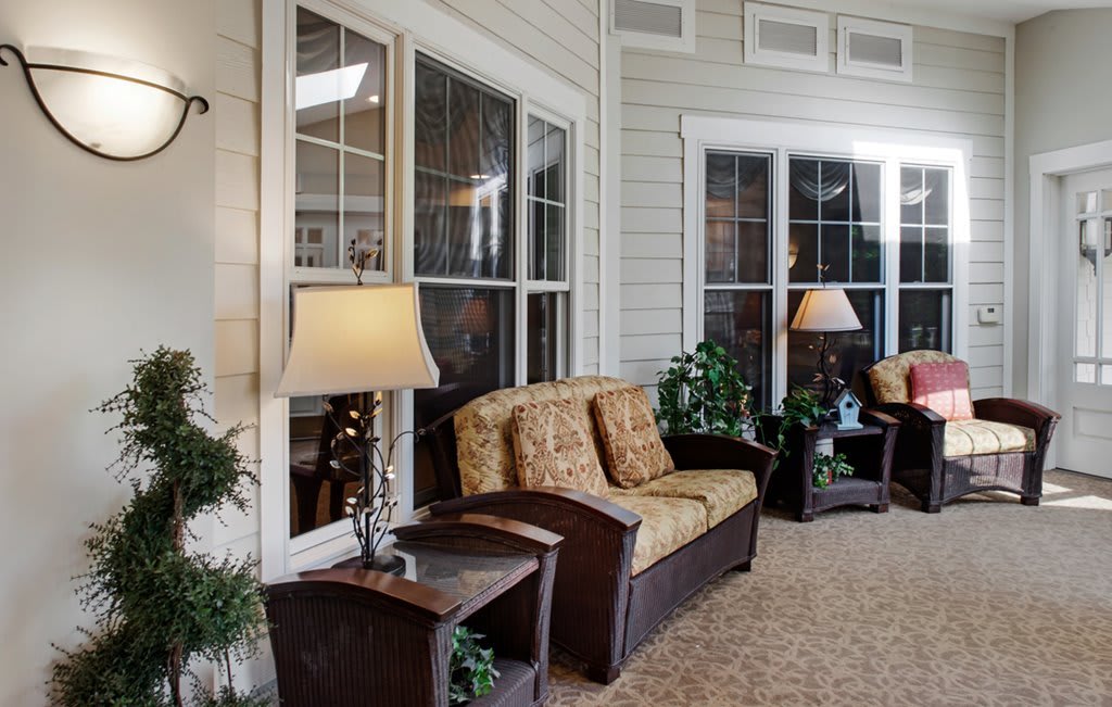 A cozy living room with comfortable seating, lamps, and lush greenery.