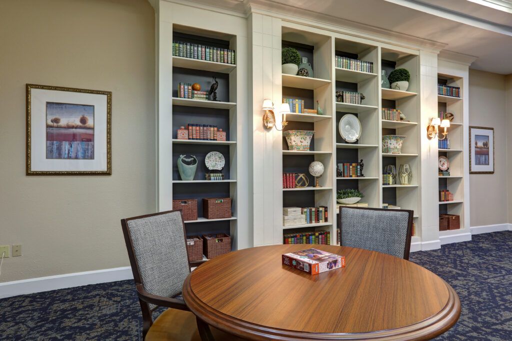 A cozy library setting with bookshelves, a round wooden table, and chairs.