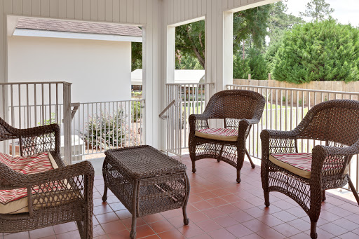 A cozy outdoor porch with wicker chairs and a table, perfect for relaxation.