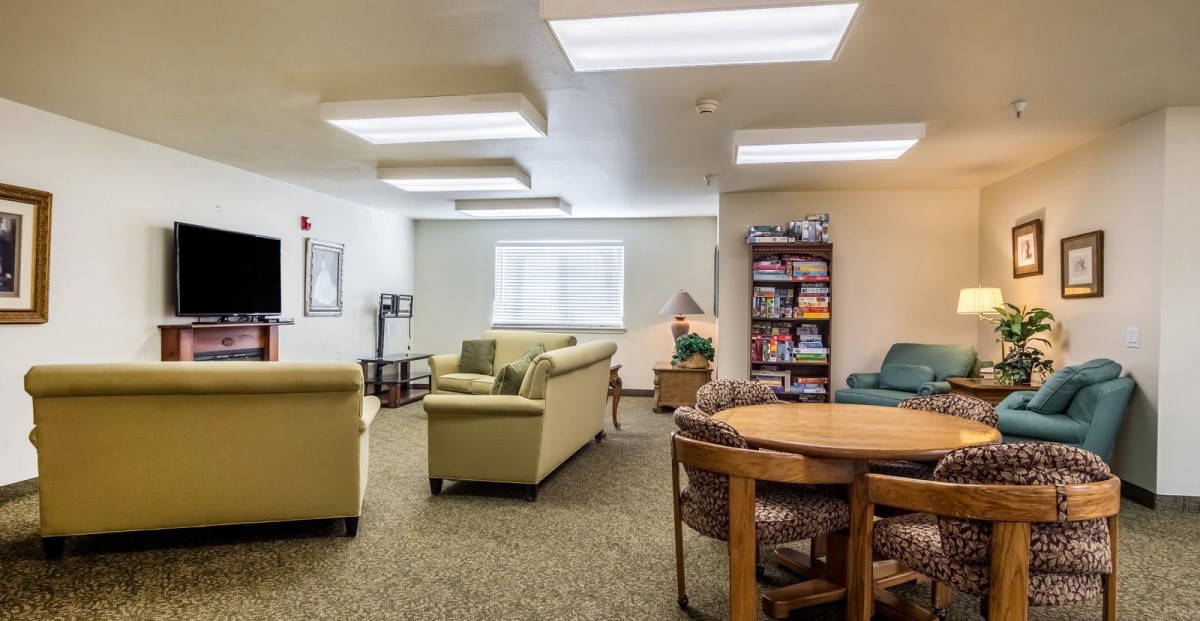 A cozy living room with comfortable seating, a bookshelf, and a circular table.