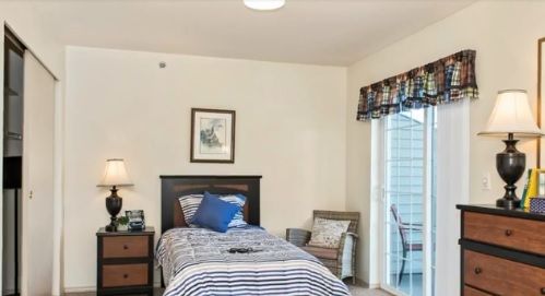 A cozy bedroom with a single bed, bedside table, and artwork on the wall.