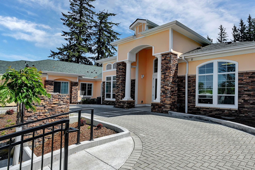 A modern residential house with a paved driveway and landscaped surroundings.