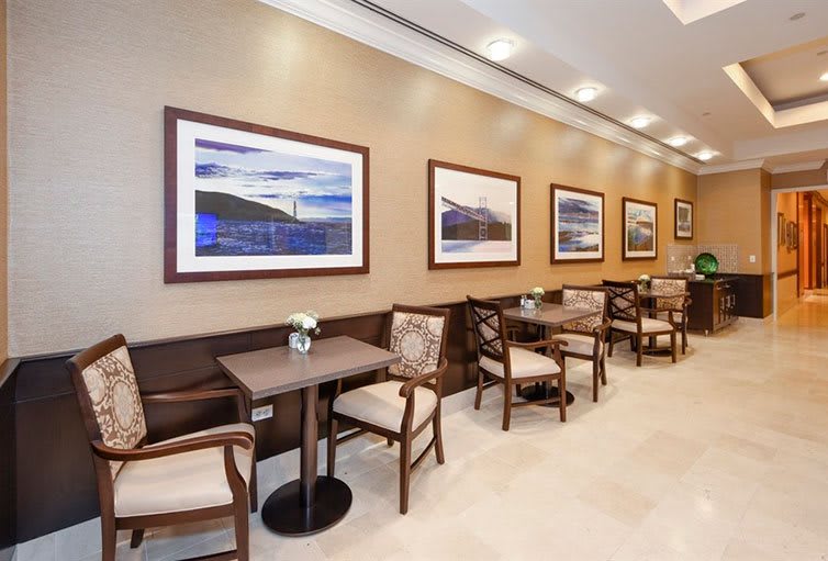 A comfortable seating area with artwork on the walls, featuring tables and chairs arranged neatly.