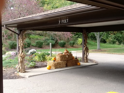 A cozy autumn display with hay bales and pumpkins under a covered area.