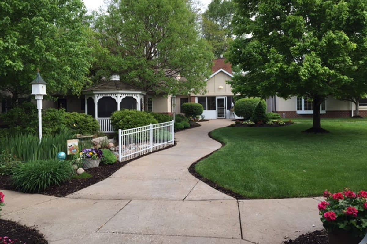 A charming house surrounded by a lush garden, featuring a gazebo and a winding pathway.